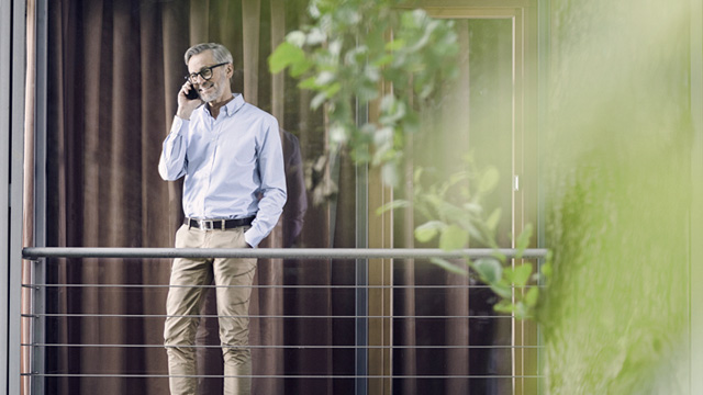 Man talking in his cell phone standing on his balcony