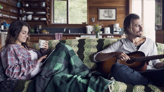 Couple sitting in sofa playing guitarr 