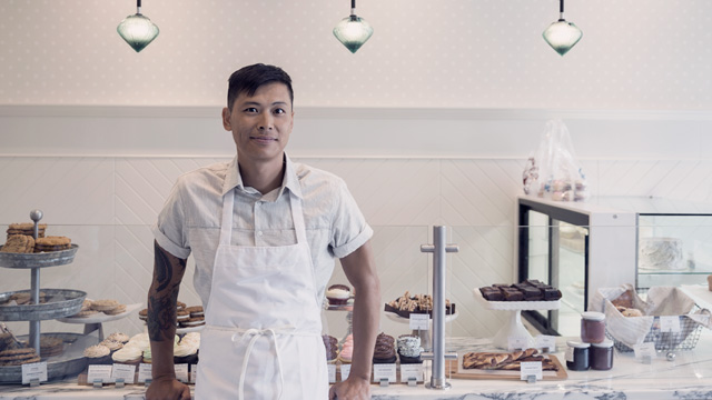 A baker showing the cakes in a bakery