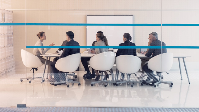 Formal office meeting with several people around a table