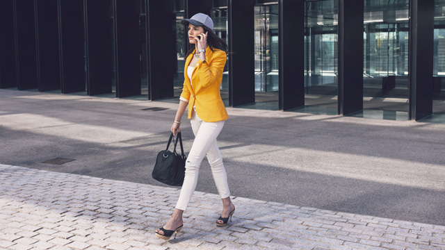 Woman outside is walking and talking in mobile 