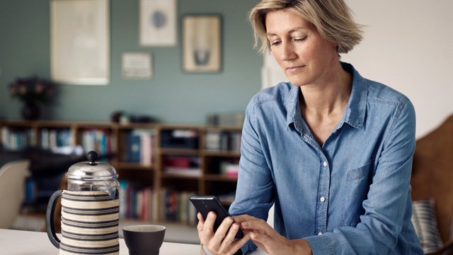 Woman smiling while looking at her mobile at home.